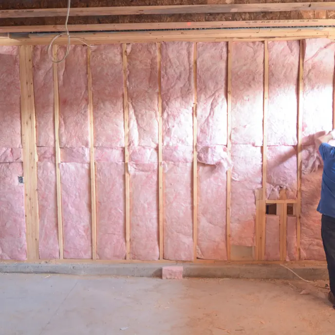A cropped photo of a Blouin Brothers technician spraying insulation foam between ceiling joists.