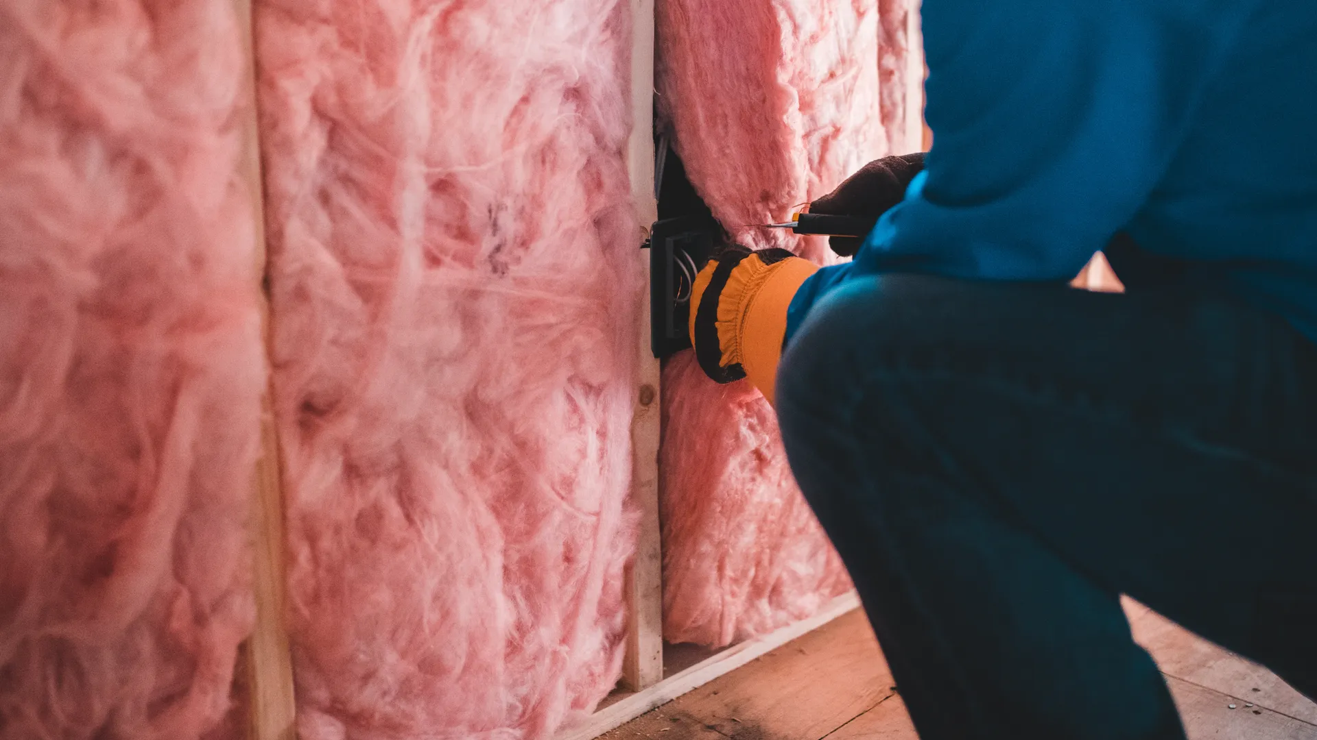 A close-up photo of insulation being installed between wall joists.